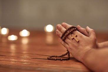 Hands with Rosary and Candles on Table